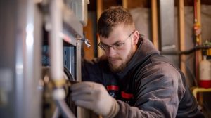 Technician inspecting furnace for repair or replacement in Meridian, ID home